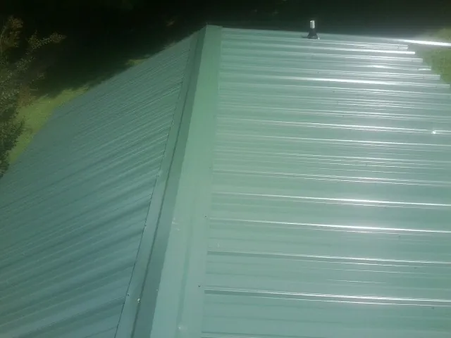New green metal panels meeting at the ridge of a roof — Flat Roof Repair work by our crew in Sandgap