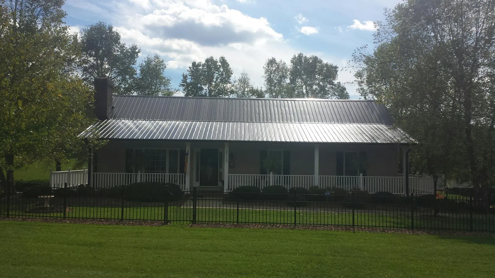 Gray metal roof on a brick ranch with a full width front porch — Gutter Guard Installation work by our crew in Sandgap