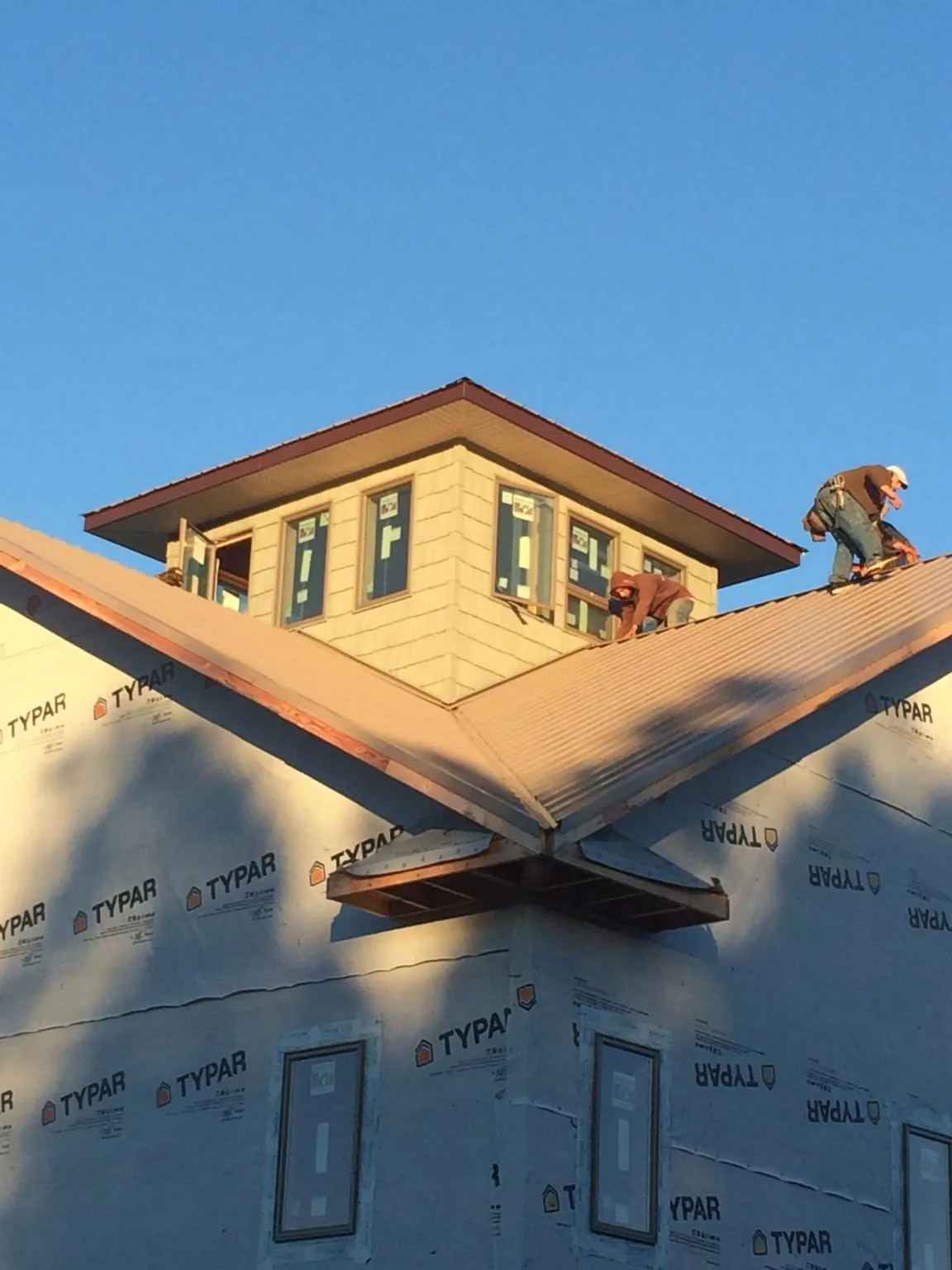 Roofers working around a rooftop cupola on a new metal roof at sunset — Roof Waterproofing in Sandgap by Roofing Brothers